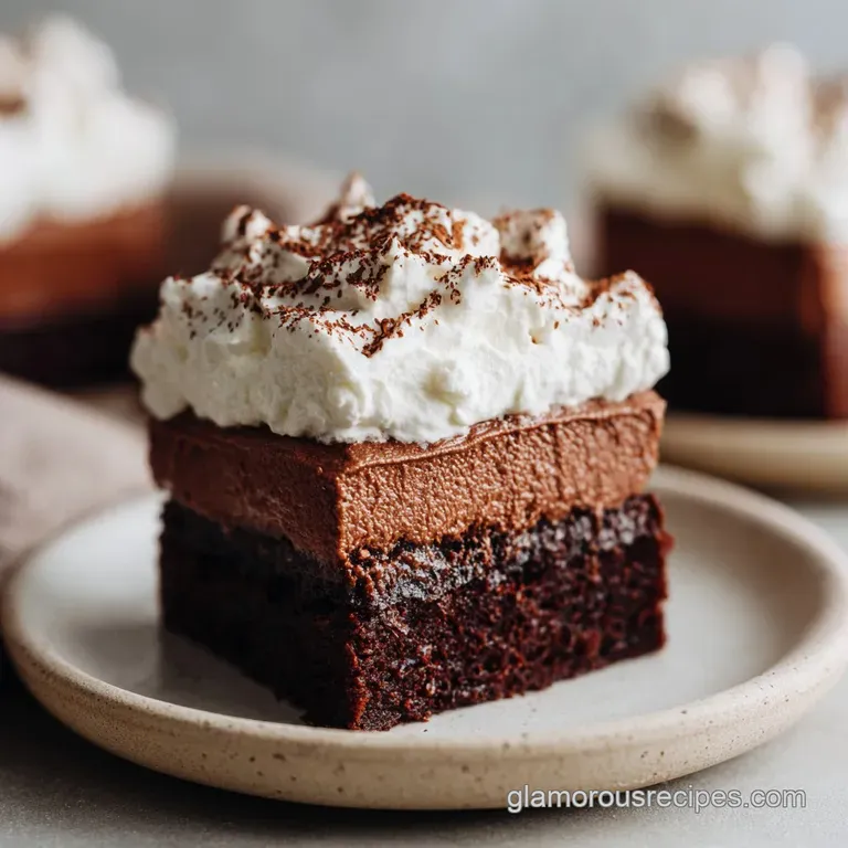 Elegant chocolate mousse brownie slice. Layers of dark brownie, light mousse, topped with cocoa powder and chocolate shavi...