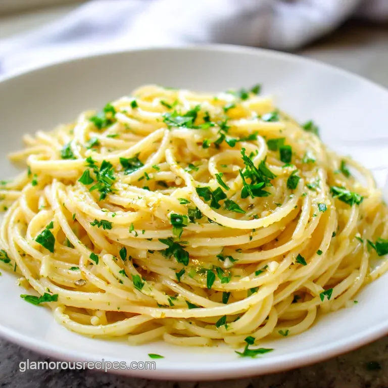 Elegant plate of twirled spaghetti aglio e olio topped with fresh parsley and a drizzle of olive oil against a dark backgr...